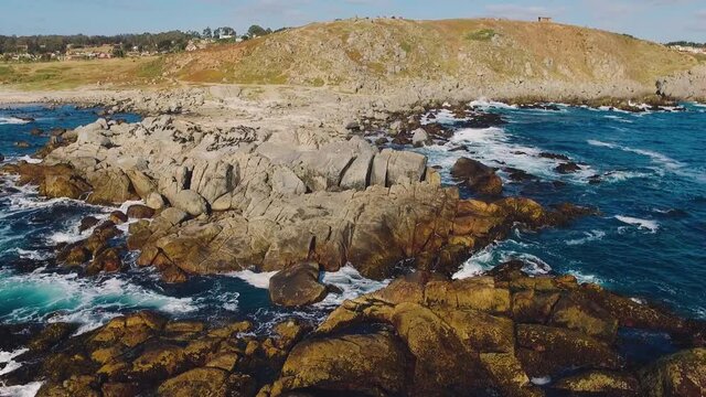 Aerial drone shot over the Chilean beach, cinematic and stabilized video moving over the rocks as they are hit by waves