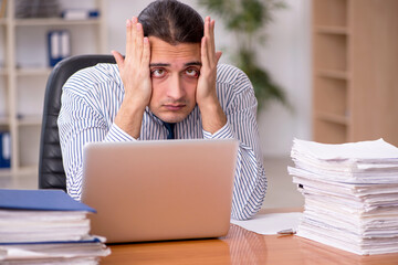 Young male employee unhappy with excessive work in the office