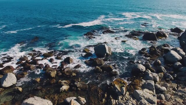 Aerial drone shot over the Chilean coast, cinematic and static stabilized video over the waves hitting the rocks
