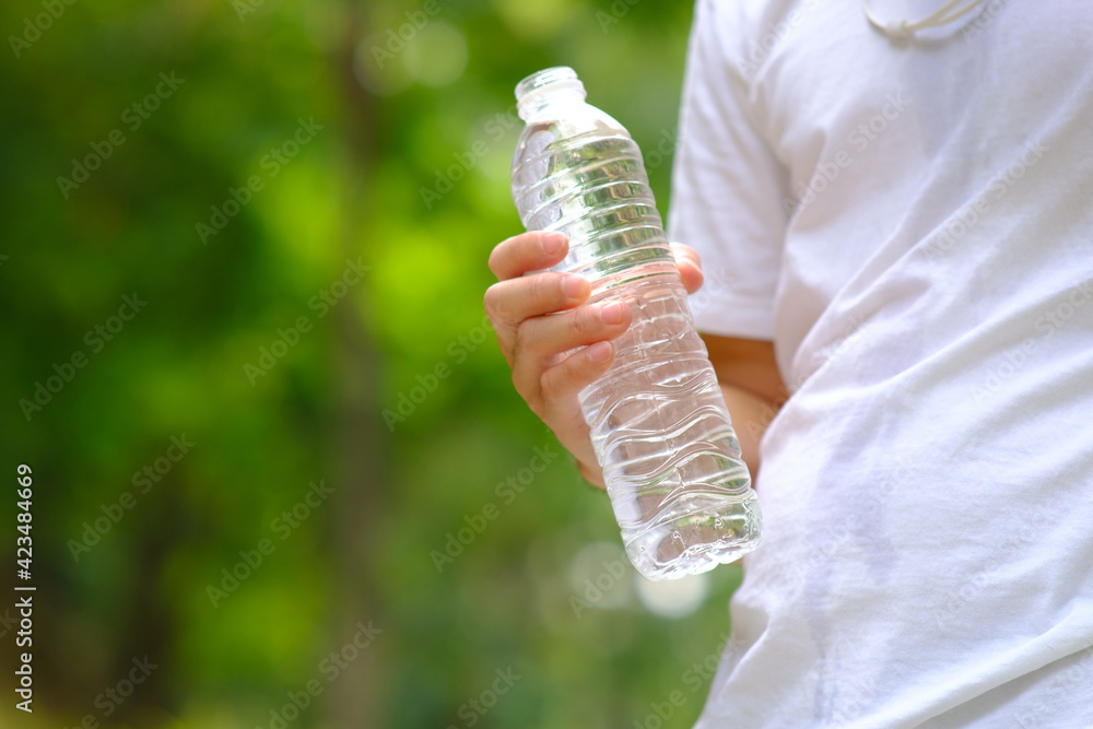 Poster bottle of water in green natural background and space