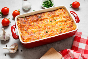 Classic italian made ground beef lasagne topped with melted cheese and garnished with fresh parsley on gray background. 