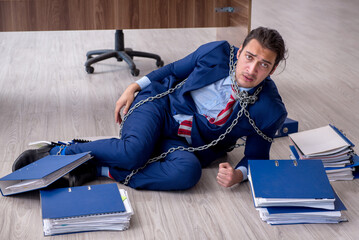 Chained male employee unhappy with excessive work in the office