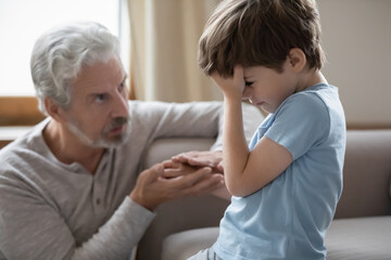 Loving mature grandfather hug hold hand of unhappy sad little 8s grandson feeling hurt offended....