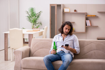 Young man drinking alcohol at home