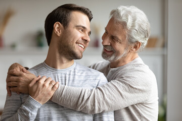 Loving senior Caucasian 60s father embrace cuddle grownup adult son show parent support and care....