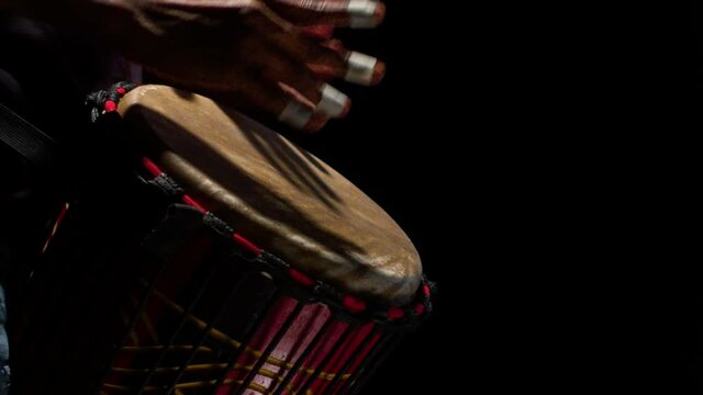 Black man drummer rhythmically beats hands on the African drum in the studio, close-up. Concept of drum musical instruments.