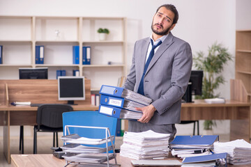 Young businessman employee unhappy with excessive work in the of