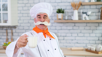Elderly milkman drinks cow's milk in the kitchen.