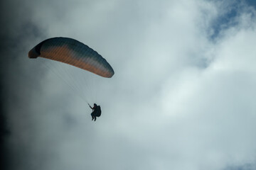 A Paraglider flying into the sky with clouds on a sunny day.