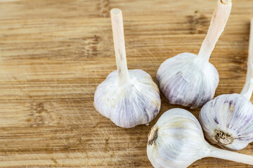 scattering of whole head of garlic on a light beige wooden background
