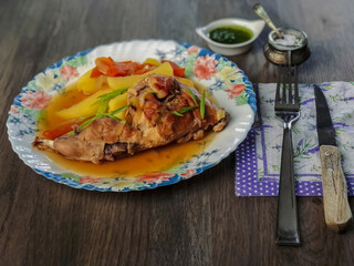 Rabbit leg stew with carrots and potatoes on wooden table with spun and knife and souse pot. Close- up photo.
