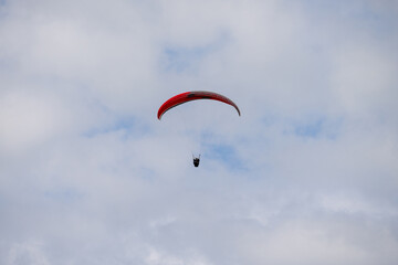 A Paraglider flying into the sky with clouds on a sunny day.