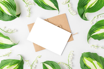 Blank greeting card in frame made of spring lily of the valley flowers on white background. Flower composition. Mock up
