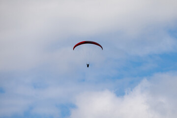 A Paraglider flying into the sky with clouds on a sunny day.