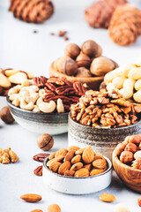 Assortment of nuts in bowls. Cashews, hazelnuts, walnuts, pistachios, pecans, pine nuts, peanuts, macadamia, almonds, brazil nuts. Food mix on gray background, copy space