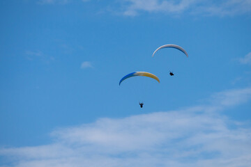 Two para gliders flying on a cloudy day.