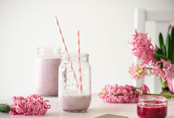 berry smoothie in a jar on a light background with hyacinth flowers