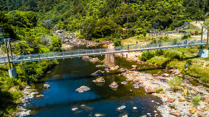 Fototapeta premium Cable bridge across mountain river. Coromandel, New Zealand.