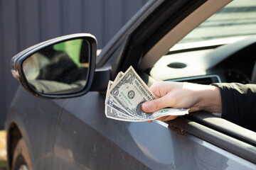 a woman's hand pulls out a dellara from a car window, corruption and bribes