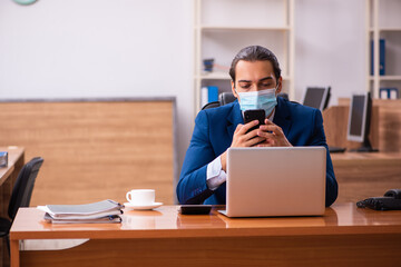 Young male employee working in the office wearing mask