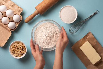 Baking ingredients flour, eggs, butter with rolling pin on a bright background.