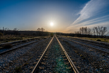 Fototapeta na wymiar railway in the countryside with the sun and the blue sky