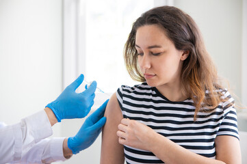 Doctor applying a vaccine on a woman's arm .