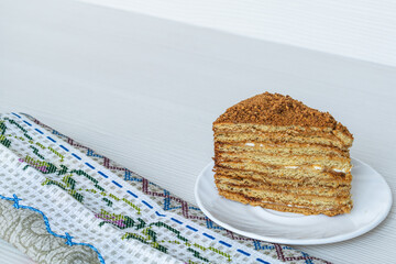 A slice of honey cake close-up on a light background. Place for an inscription.