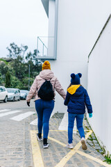 mother and daughter hand in hand with their backs to each other in winter clothes walking in the street