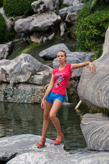 Fototapeta na wymiar Beautiful girl in a pink t-shirt in a tropical garden