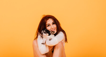 Naklejka premium Young woman cuddling chihuahua puppy in studio