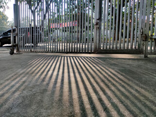 Abstract background shadow line of fence iron bars on cement surface.