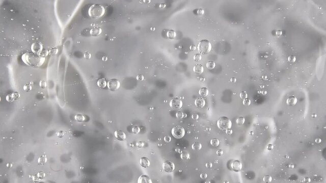 Transparent liquid gel background, clear serum texture. Motion, rotation of the beauty skincare product sample with bubbles. Top view. Macro Shot. High quality 4k footage