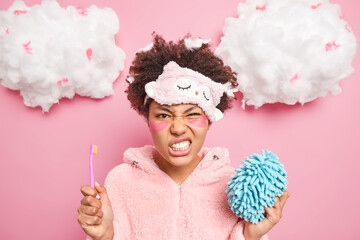 Dissatisfied dark skinned young woman with Afro hair smirks face feels annoyed hates morning...