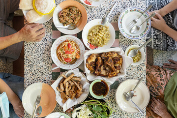 Family eating lunch, papaya salad, sticky rice, grilled chicken, fried pork lunch. Top view.
