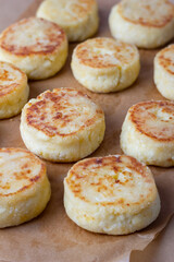 Close-up of cottage cheese pancakes on baking paper, just taken out of the oven. Traditional Russian dish syrniki, healthy breakfast food.