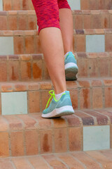 Fototapeta na wymiar Legs of a girl in sneakers and sports leggings, jogging in the fresh air, healthy lifestyle, running up the stairs