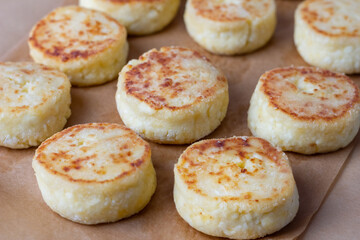 Close-up of cottage cheese pancakes on baking paper, just taken out of the oven. Traditional Russian dish syrniki.