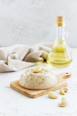 Vegan cashew cheese on a wooden board with a bottle of oil.