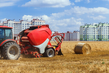A round baler discharges a fresh wheat bale