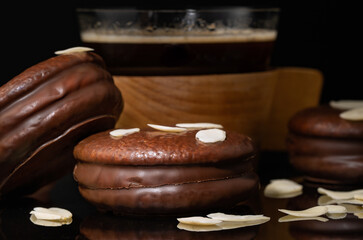 airy chocolate cake cookies with a cup of coffee on a black background. Close-up of mini cakes covered in chocolate.