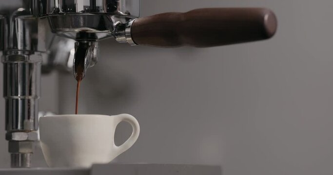 Slow motion man making espresso with single spout portafilter on coffee machine
