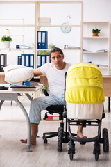 Young male employee looking after newborn at workplace