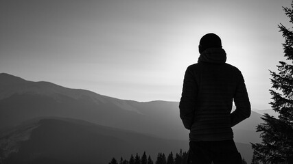 winter hike in the mountains, silhouette of a tourist at sunset