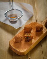 chocolate truffles or energy protein balls made with dry dates, walnuts, raisins, covered by cocoa powder and sesame seeds