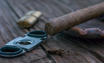 Fragment of cut cigar with ashtray and guillotine on vintage wooden table