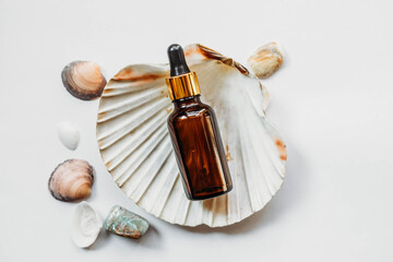 brown little bottles of essential oil on big shell on white background 