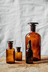 brown glass bottles of essential oil on wooden table, on white background 