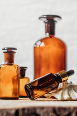 brown glass bottles of essential oil on wooden table, on white background with shell from close up