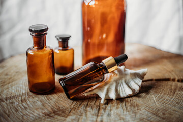 brown glass bottles of essential oil on wooden table, on white background with shell